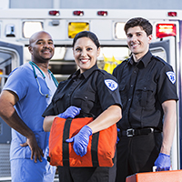 Smiling medical team standing together in front of an ambulance